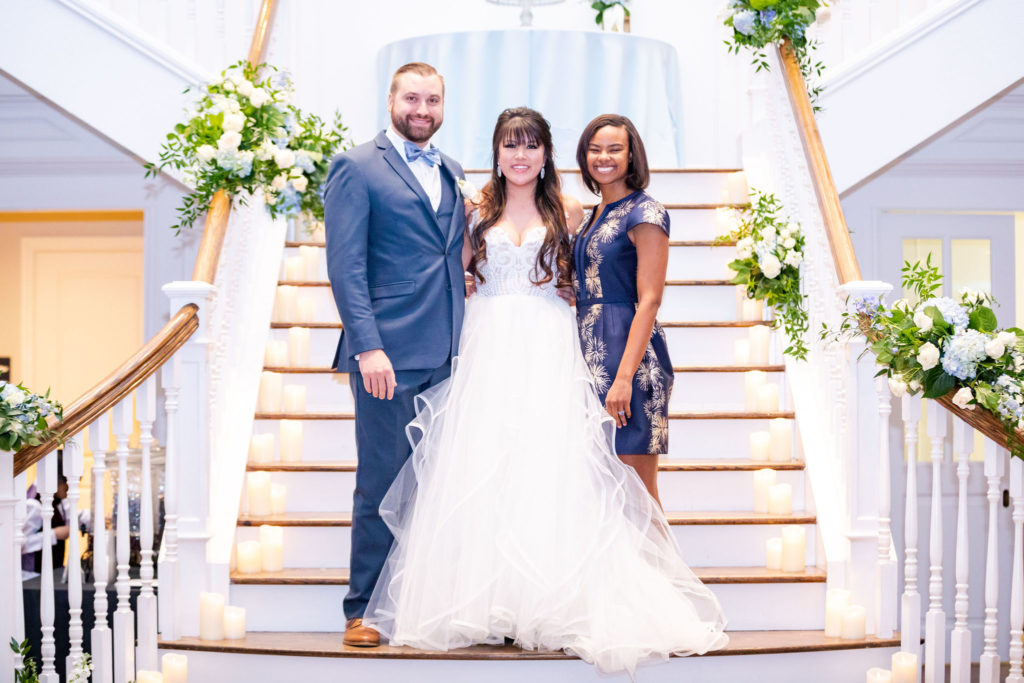 Bride and Groom take a photo with Helayne Nicholson on the venues staircase