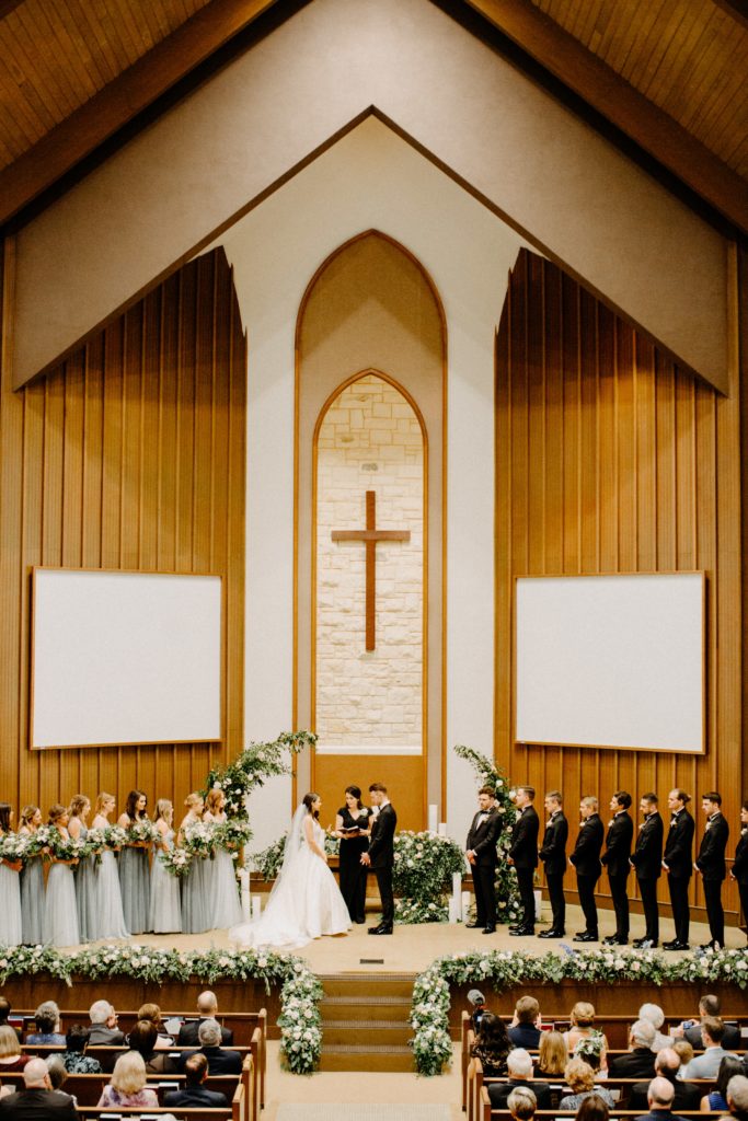 Bride & Groom framed by asymmetrical arch and stage floral