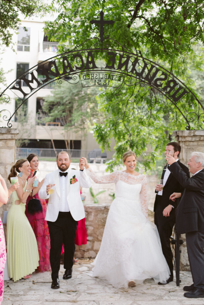 Newlyweds entering their reception as guests cheer and raise a glass to their happiness