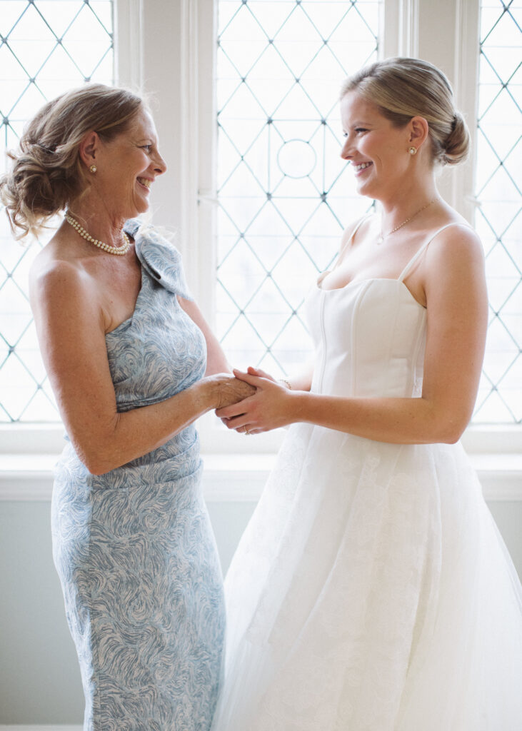 Bride and her mom smiling on her wedding day after planning together

