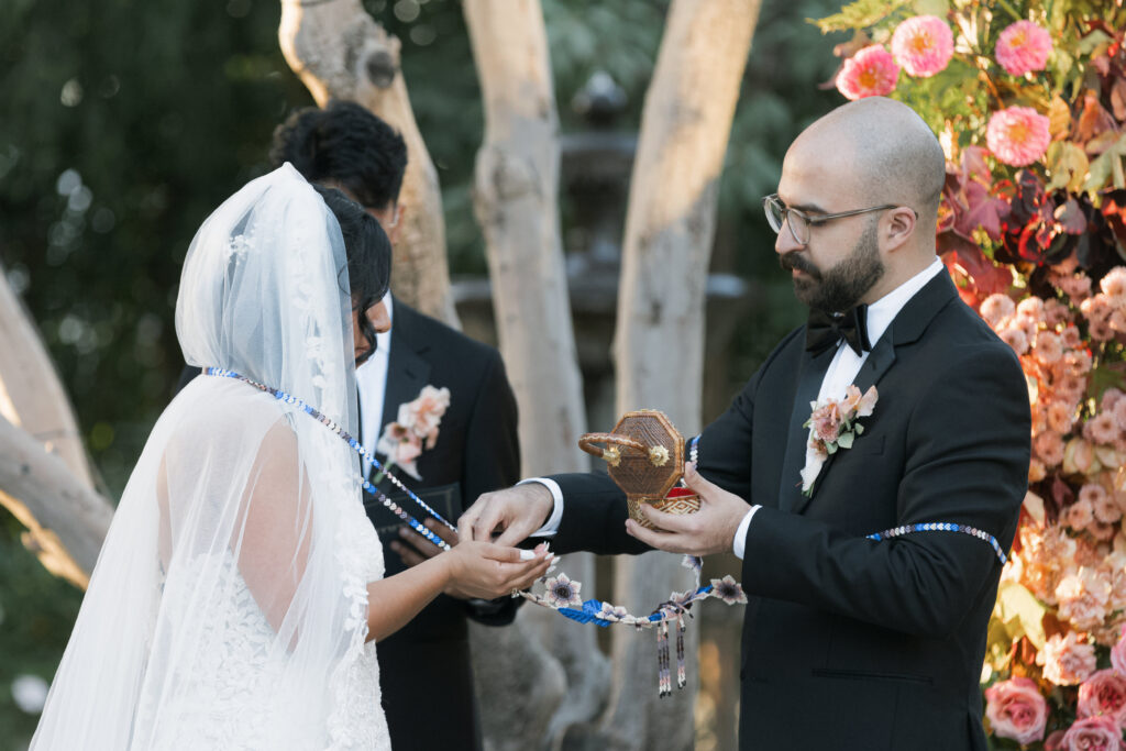 Couple participating in a Hispanic wedding tradition, debunking the wedding planning myth that traditions can't be done in a way that speaks to you as a couple.